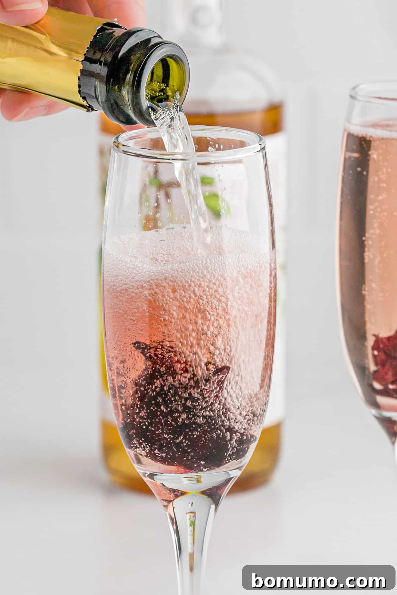 Champagne being poured into a hibiscus mimosa, creating a beautiful bubbly effect.