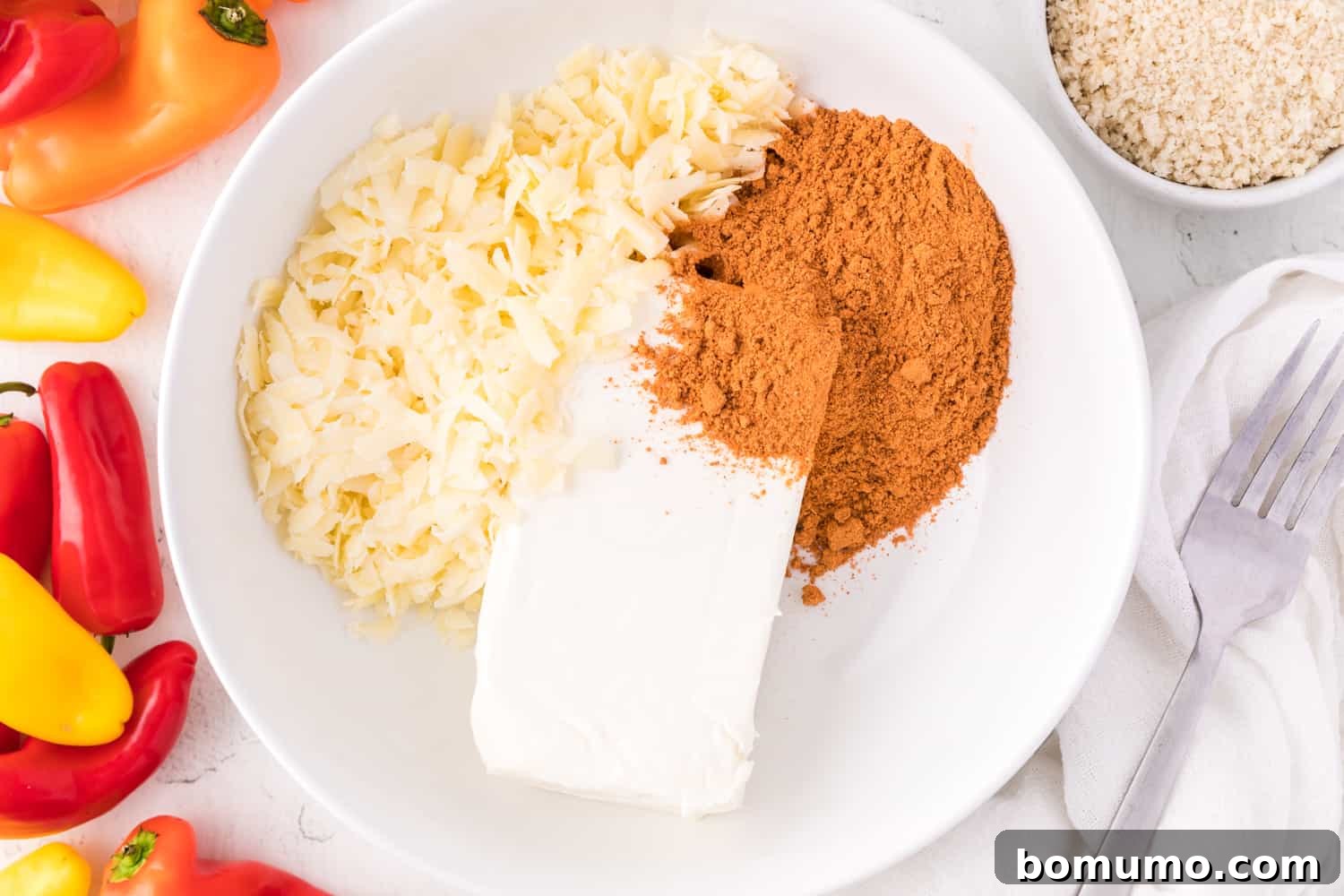 Close-up of the creamy filling ingredients – cream cheese, shredded cheddar, and taco seasoning – perfectly blended in a white mixing bowl.