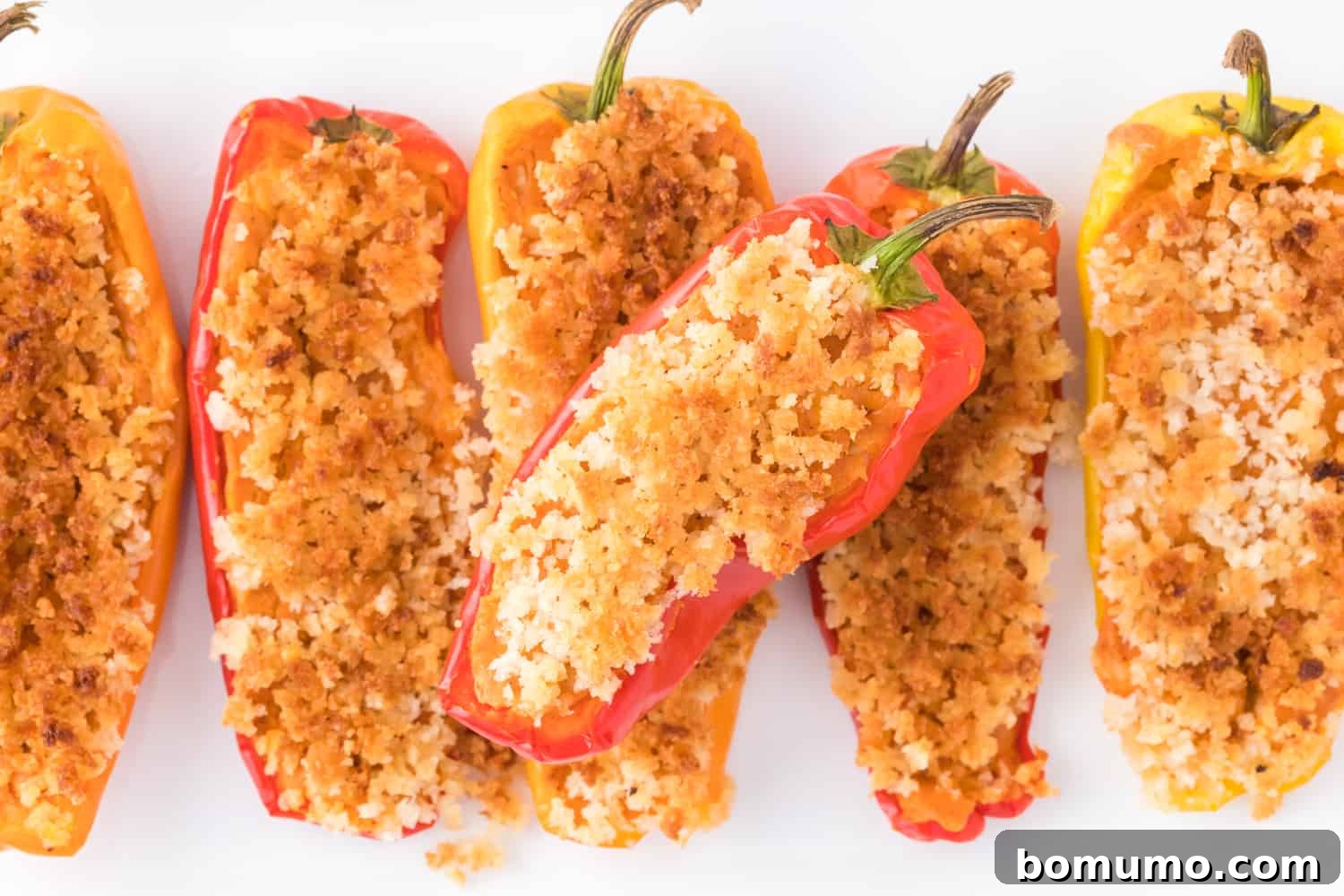 A beautifully presented pile of Southwestern stuffed mini sweet peppers on a pristine white background, showcasing their vibrant colors and crispy topping.