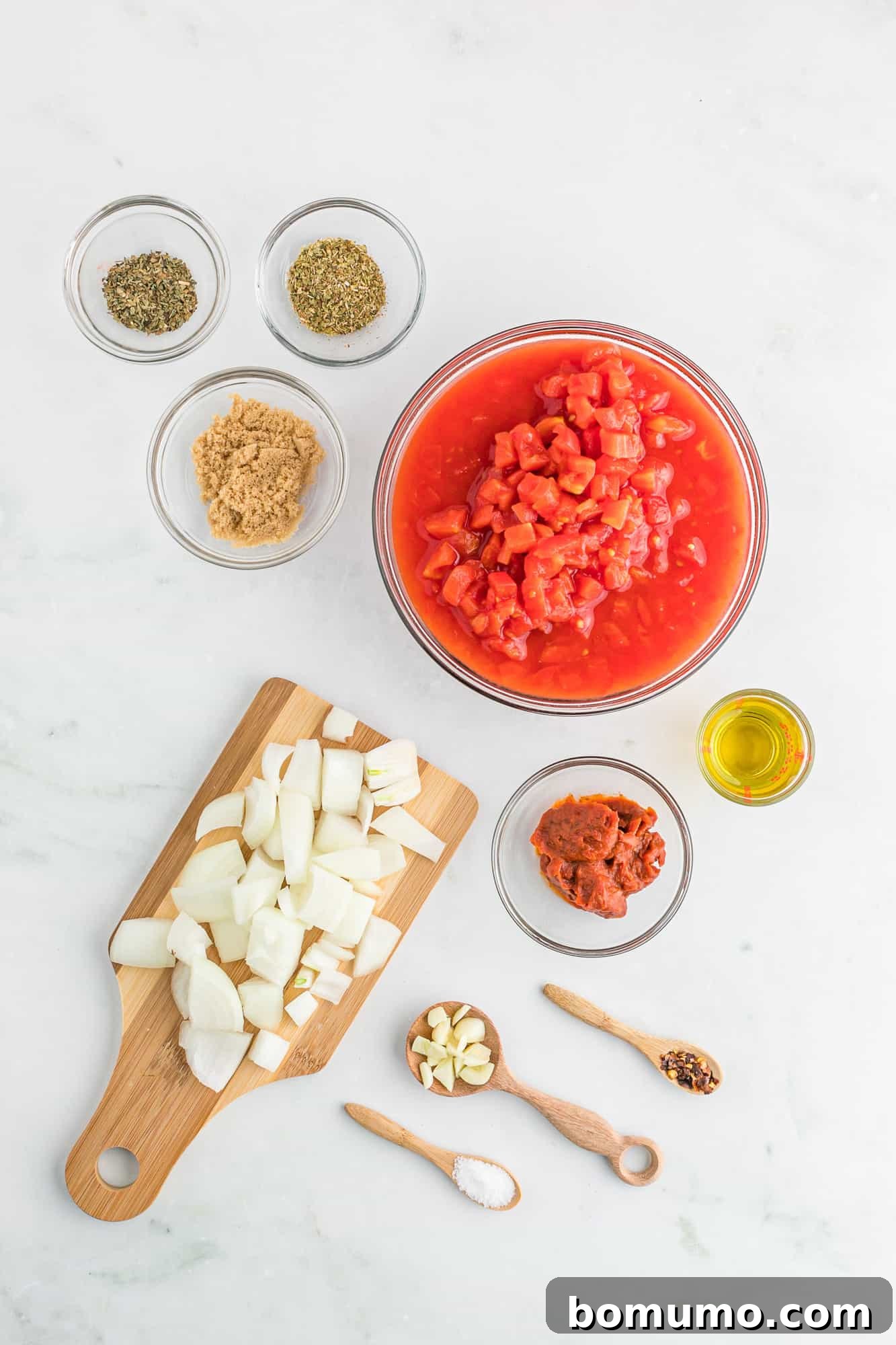Individual bowls holding precisely measured ingredients for homemade pizza sauce, including onions, garlic, canned tomatoes, and spices.