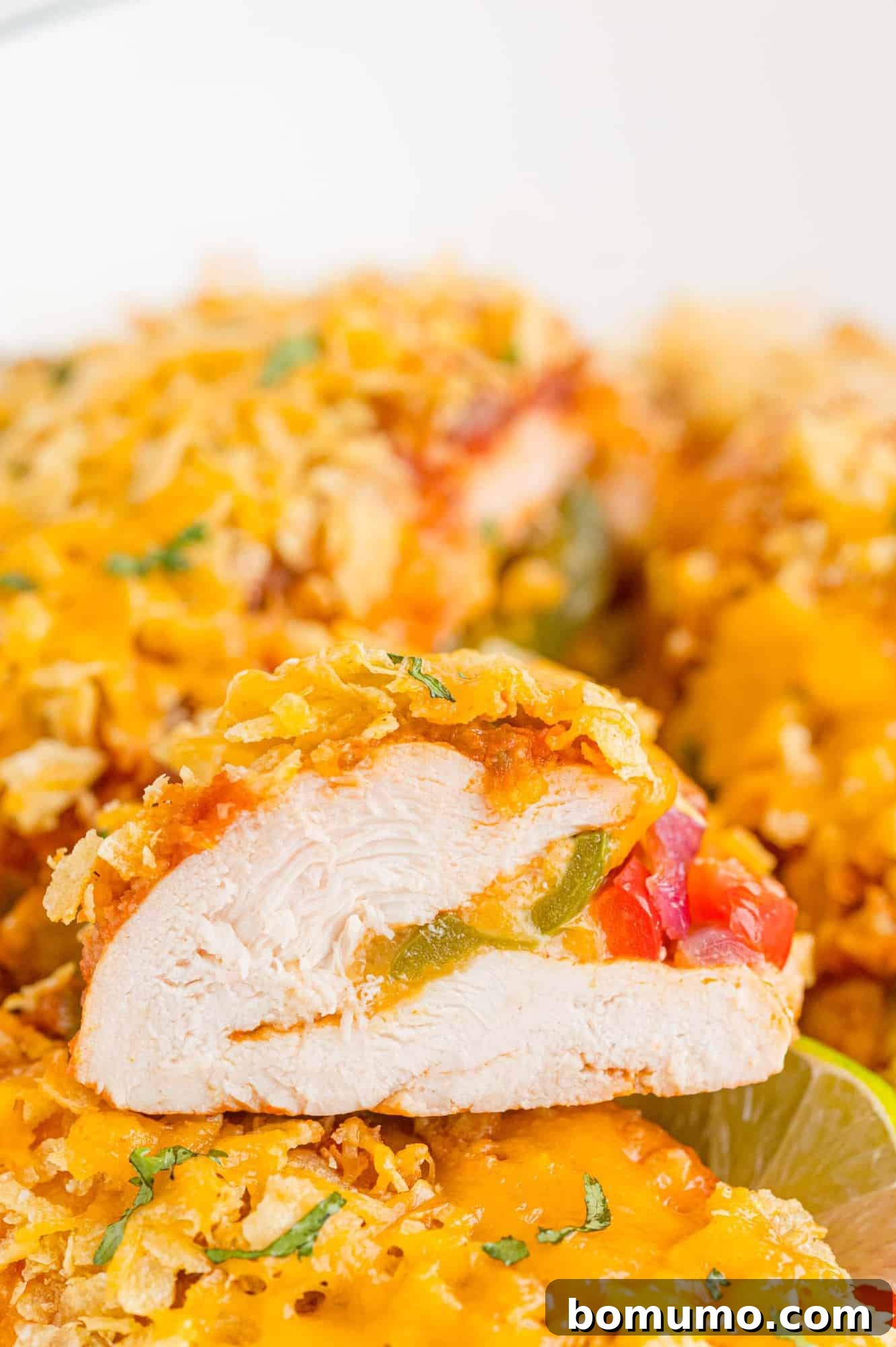 Stuffed chicken with bell peppers, onions, and a topping of chips and cheese, ready to be served.
