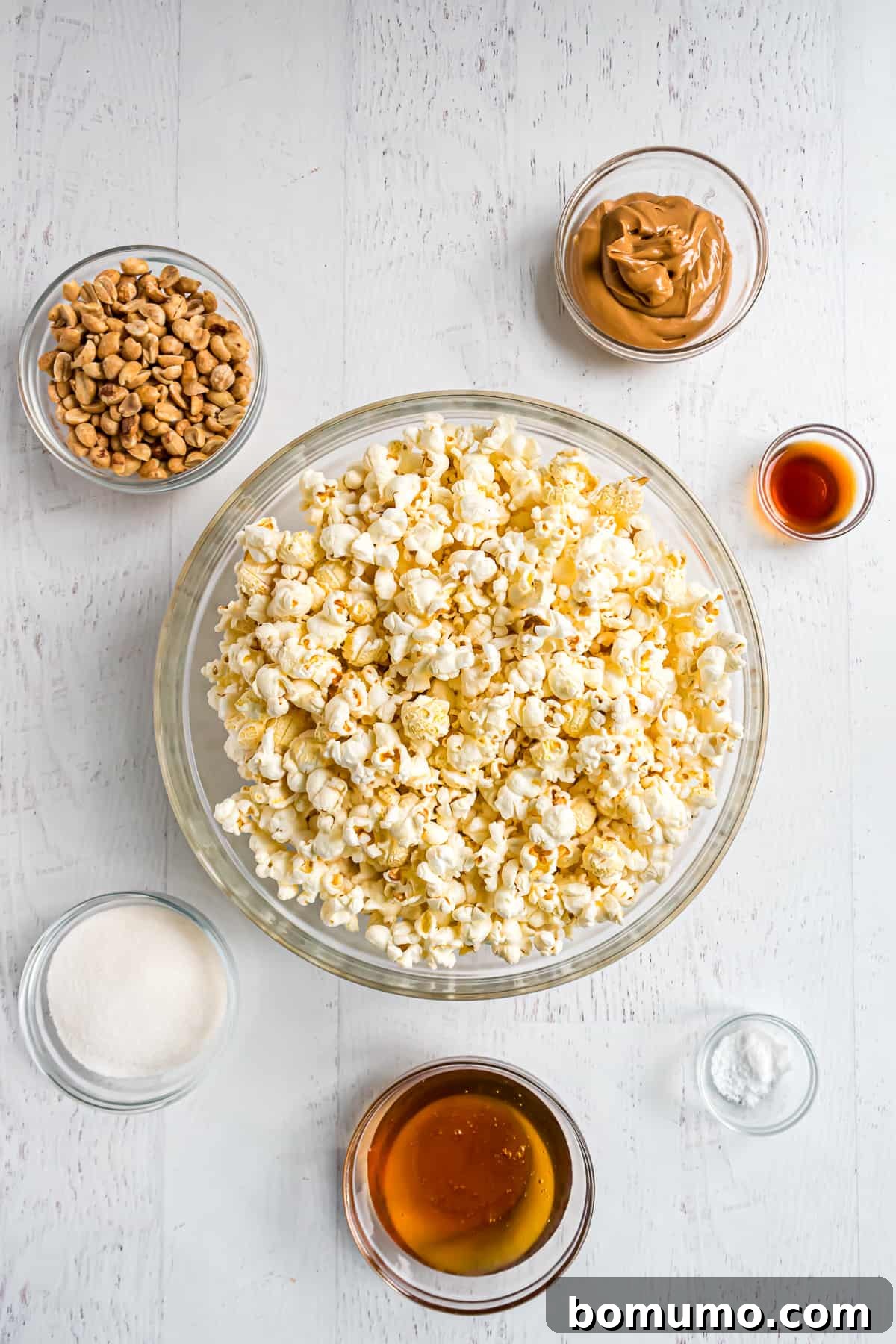 All the essential ingredients for peanut butter popcorn laid out, including popped popcorn and creamy peanut butter.