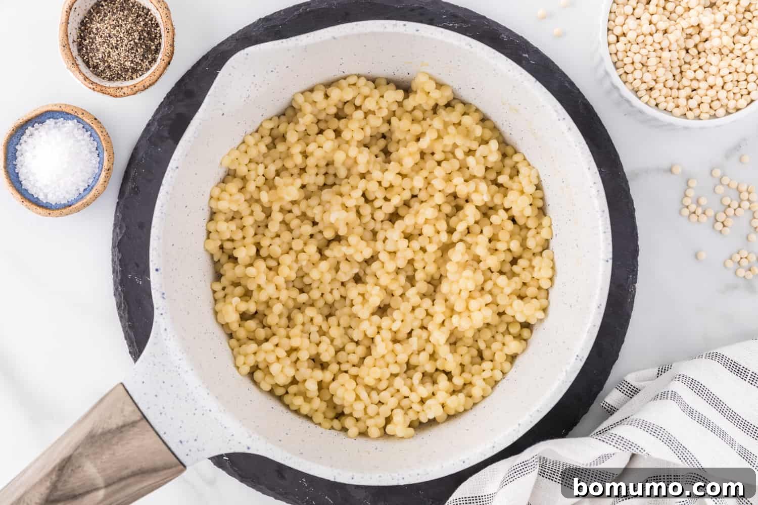Pear couscous cooked and in a strainer.