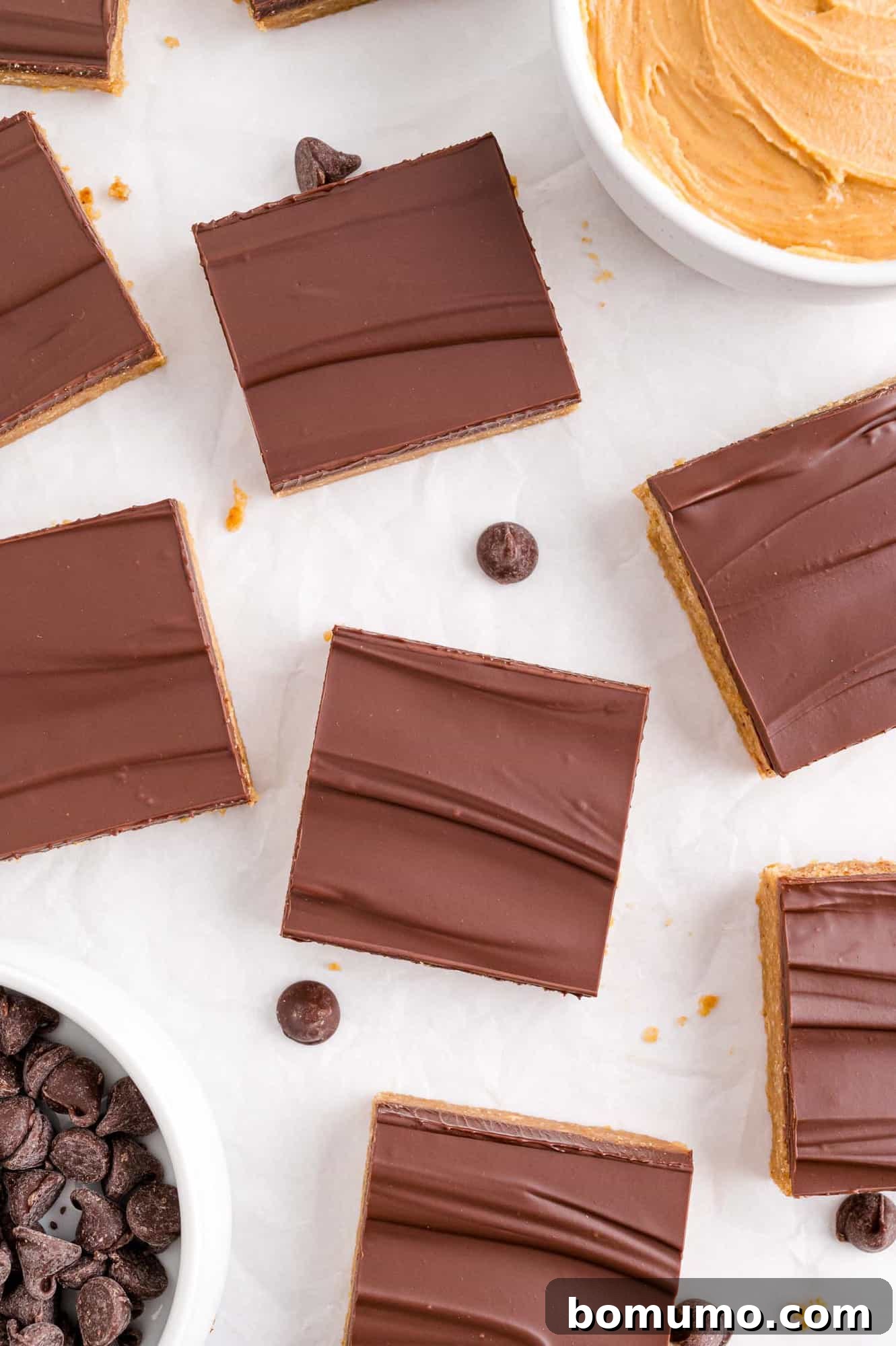 Overhead view of perfectly cut no-bake peanut butter bars with chocolate chips sprinkled on top.