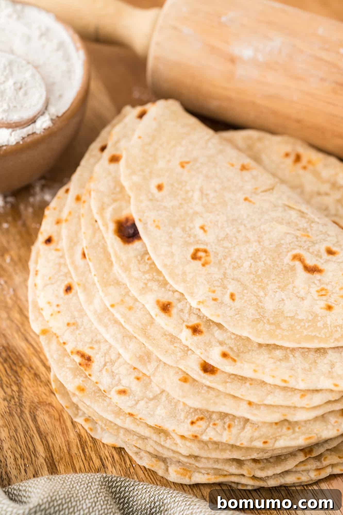 A close-up view of homemade tortillas stacked and partially folded over, showcasing their soft texture.