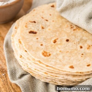 Stack of homemade tortillas in a light green linen cloth.