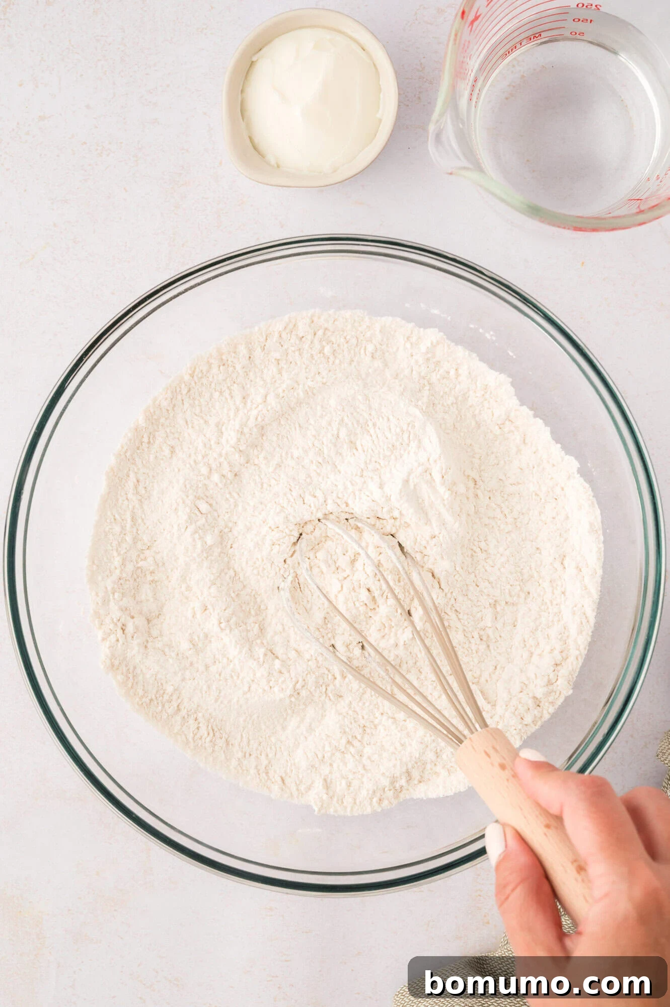Dry ingredients being mixed together with a whisk in a large bowl.