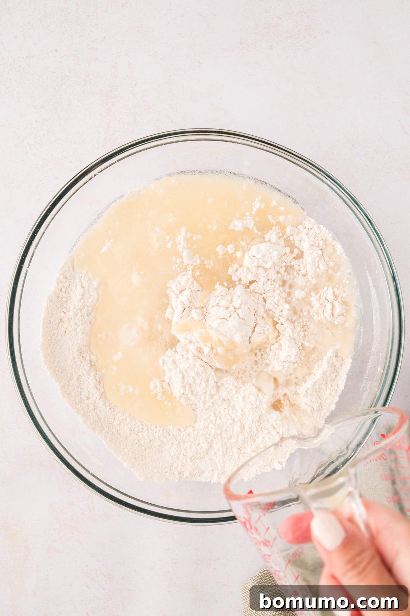 The hot water and shortening mixture being poured into the dry flour and salt.
