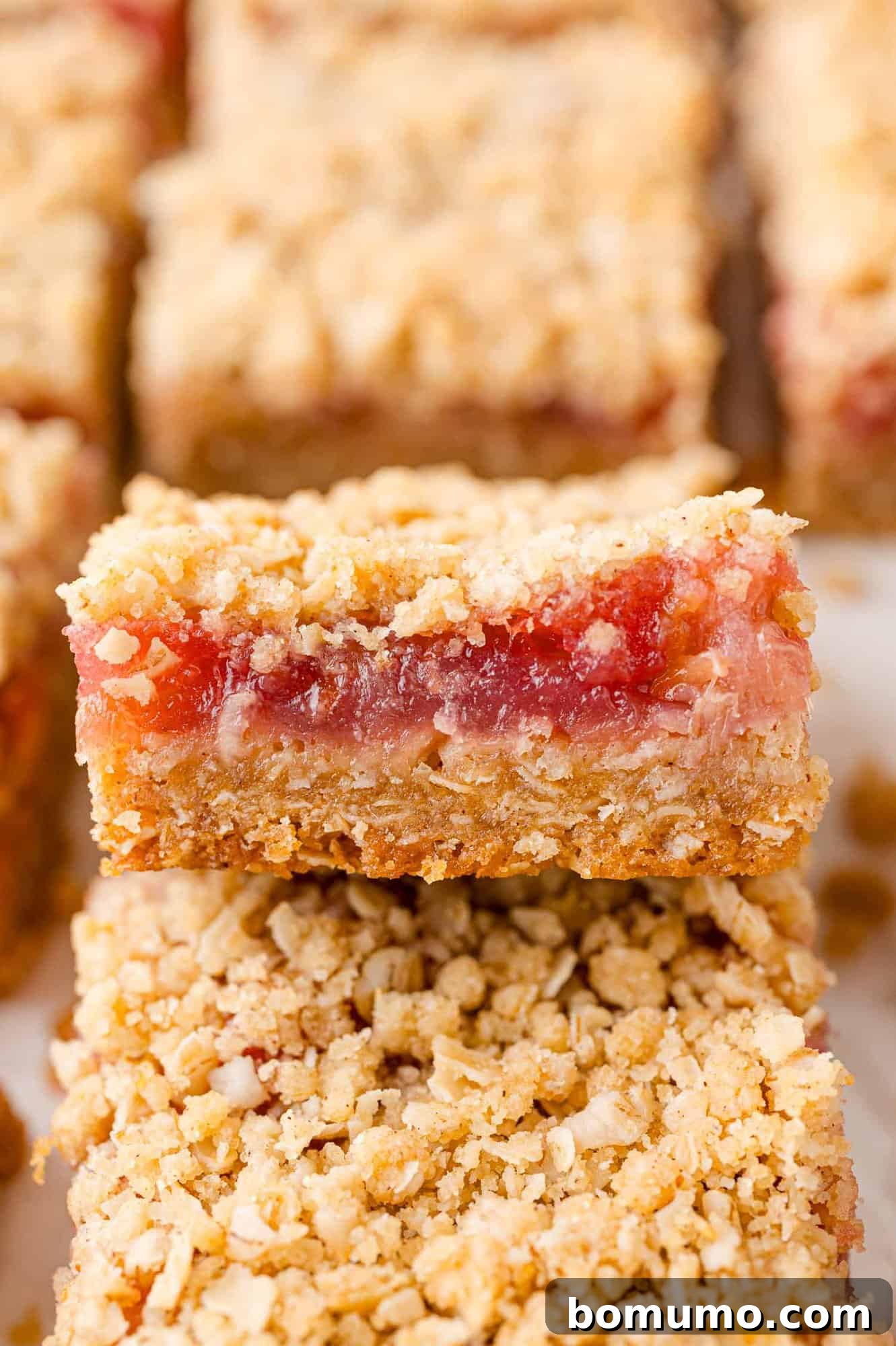 Stacked rhubarb bars with a golden, crumbly topping, showcasing their appealing texture.