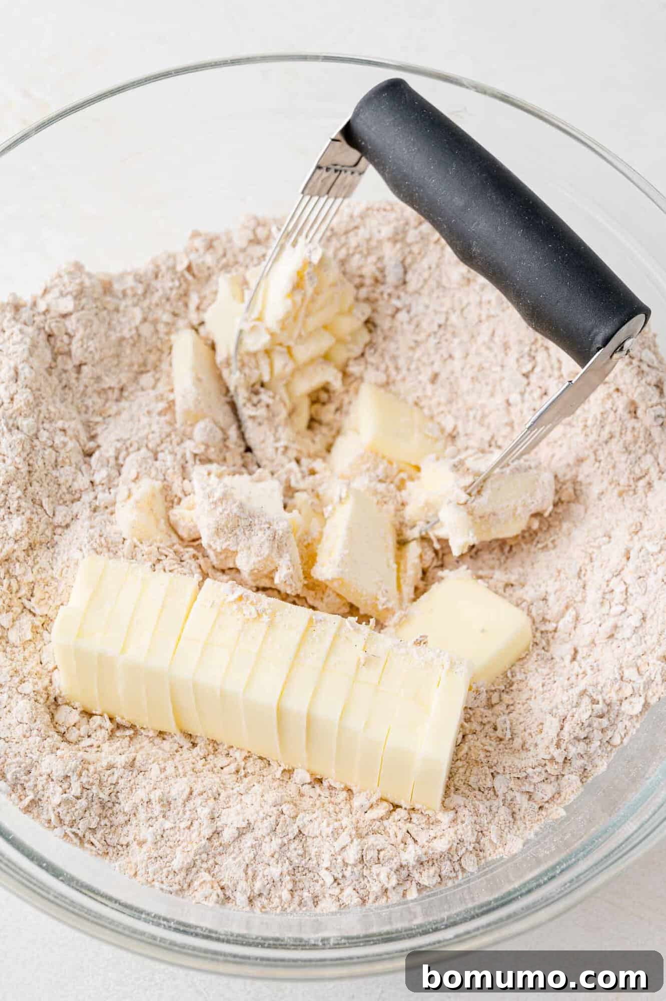 Softened butter being cut into dry ingredients for the crumb crust.