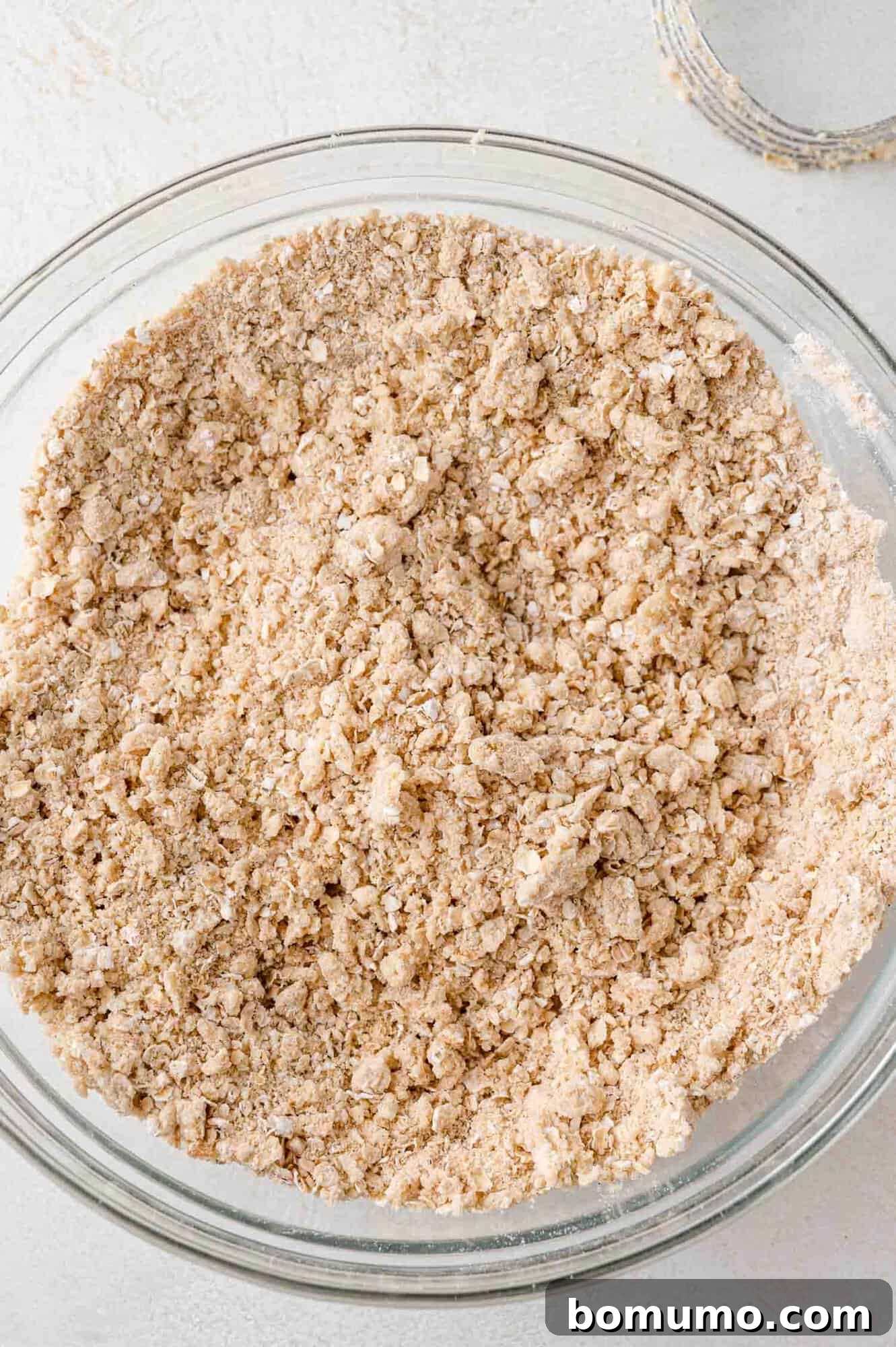 Crumb mixture in a clear mixing bowl, showing the perfect coarse texture for the crust.