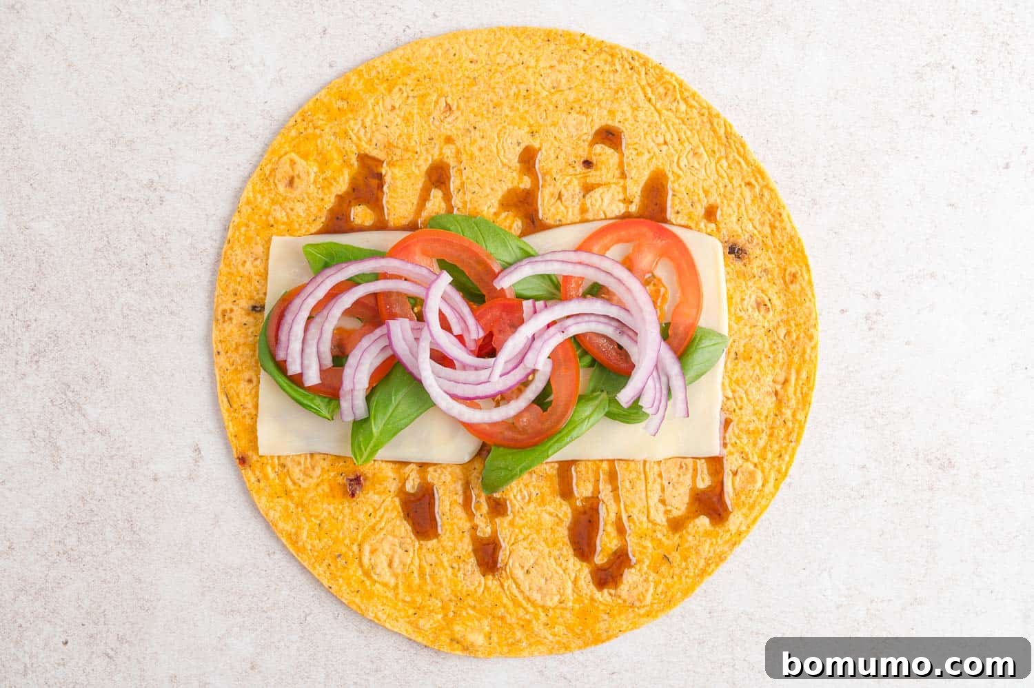 An open veggie wrap revealing layers of fresh vegetables, cheese, and a creamy spread, ready to be enjoyed.