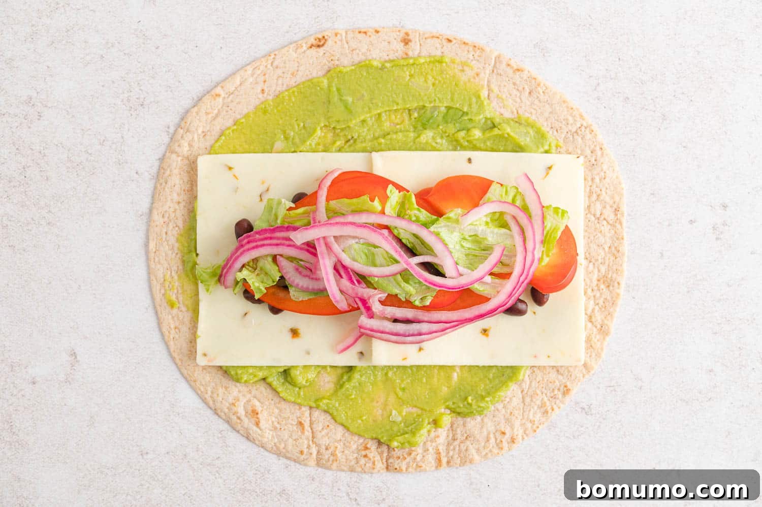 A Southwestern-style wrap, cut in half, filled with vibrant ingredients like black beans, corn, cheese, and vegetables.