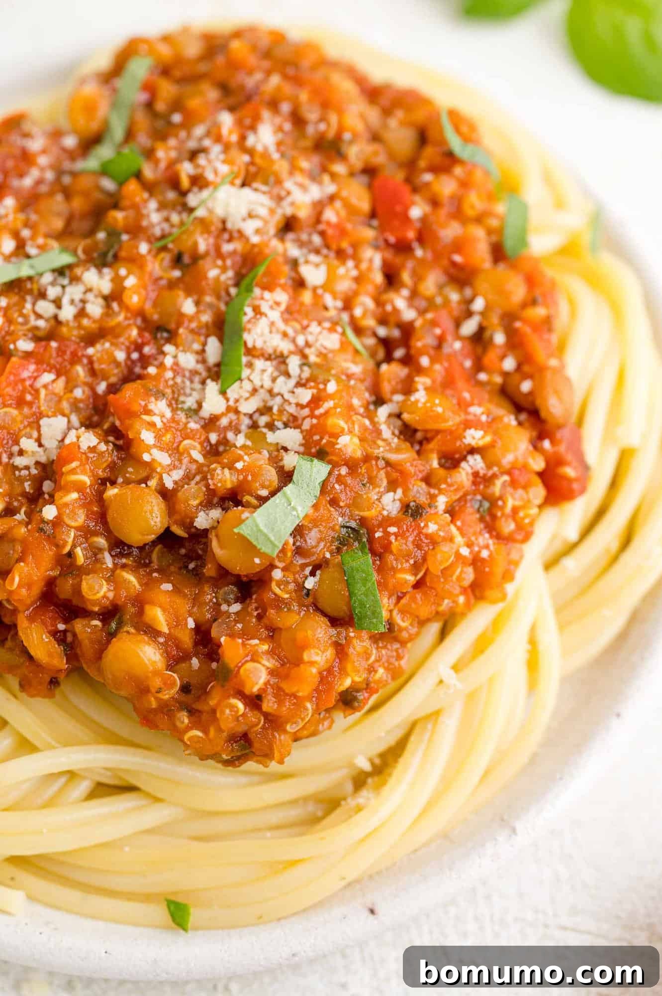 Spaghetti with rich vegan Bolognese sauce in a white bowl.
