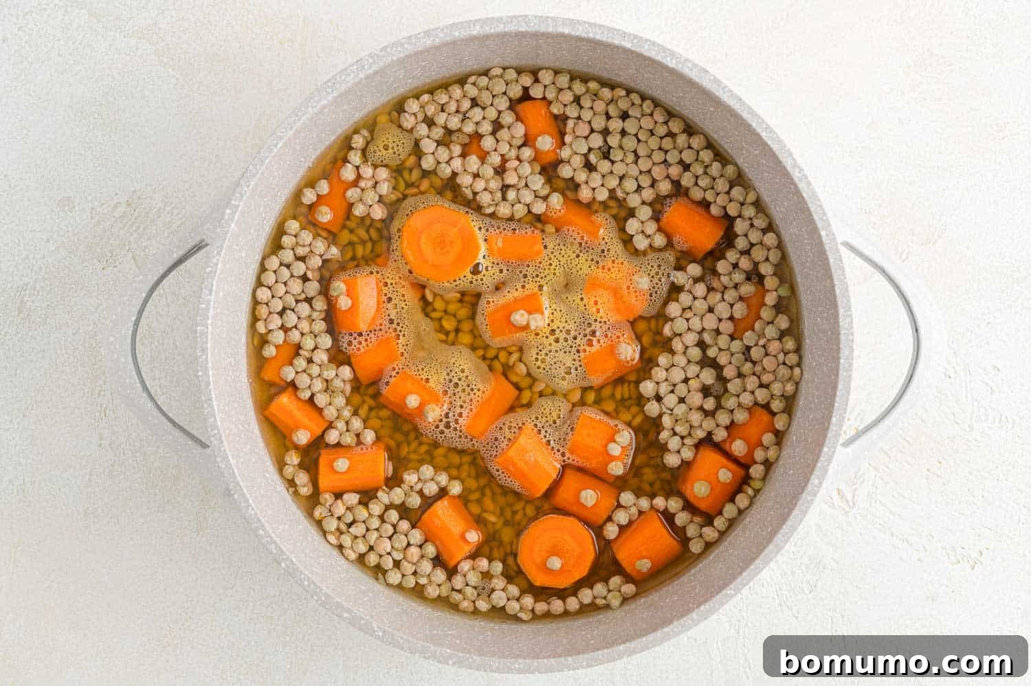 Carrots and lentils simmering in a saucepan.
