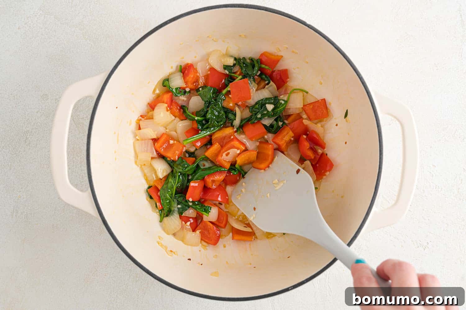 Wilted spinach with peppers and onions in a pan.