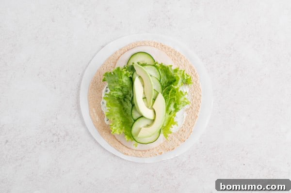 An inviting overhead perspective of a soft flour tortilla generously layered with all the fresh and vibrant turkey wrap ingredients, perfectly arranged and ready to be skillfully rolled into a satisfying meal.
