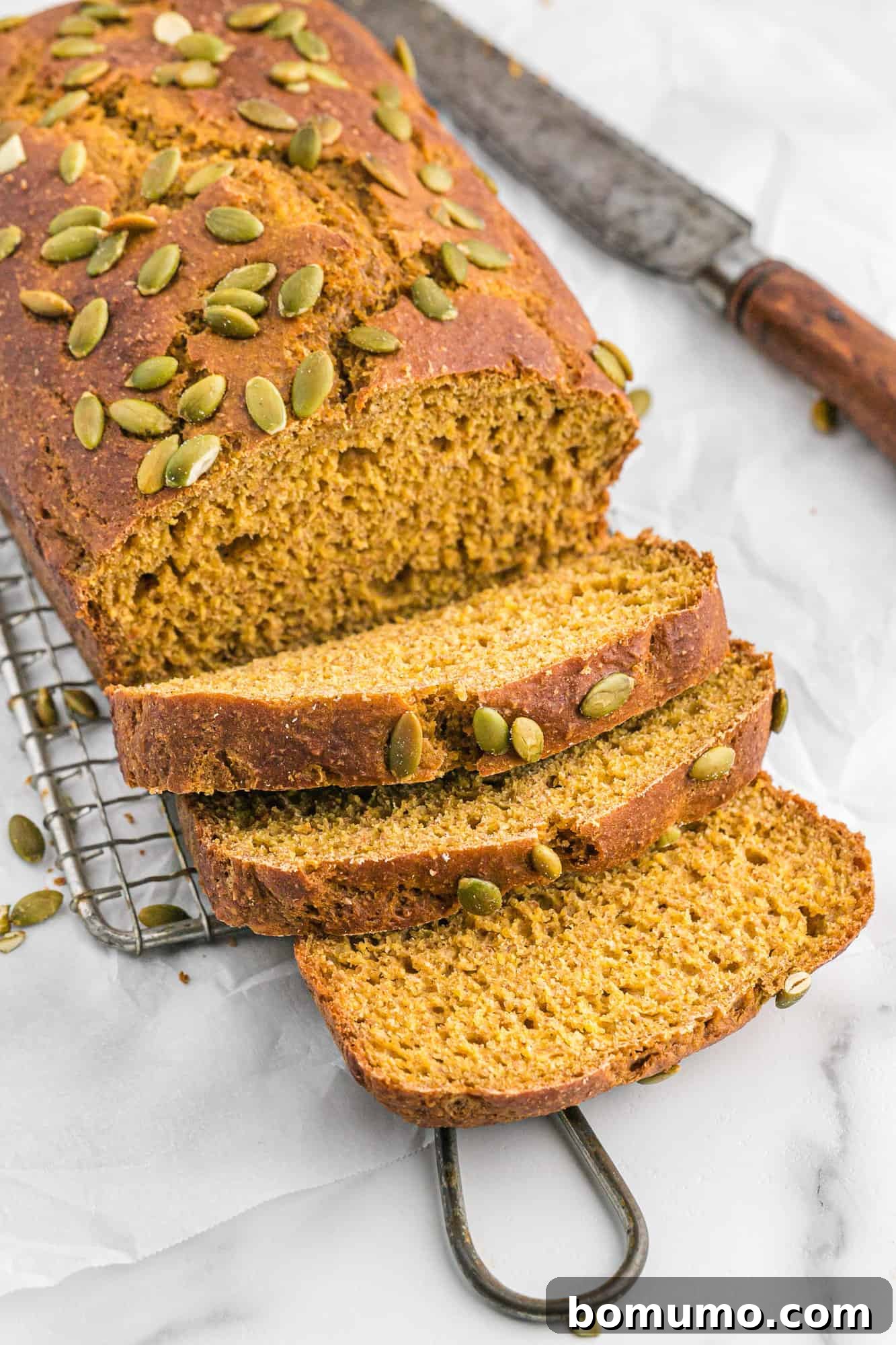 A freshly baked loaf of healthy pumpkin bread, partially sliced, showcasing its moist texture and inviting warmth.