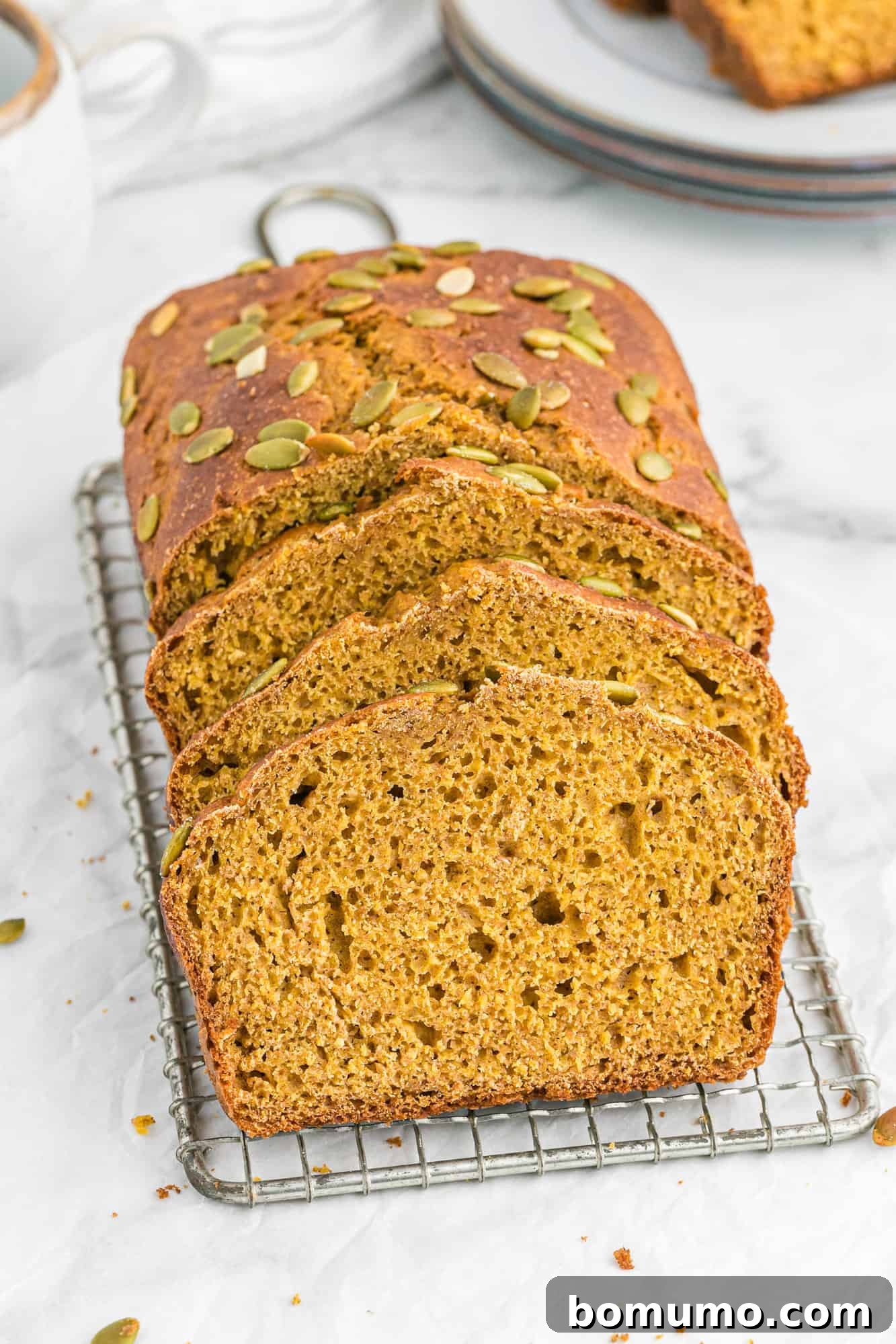 Beautifully sliced healthy pumpkin bread displayed on a pristine white surface, highlighting its soft crumb and rich color.