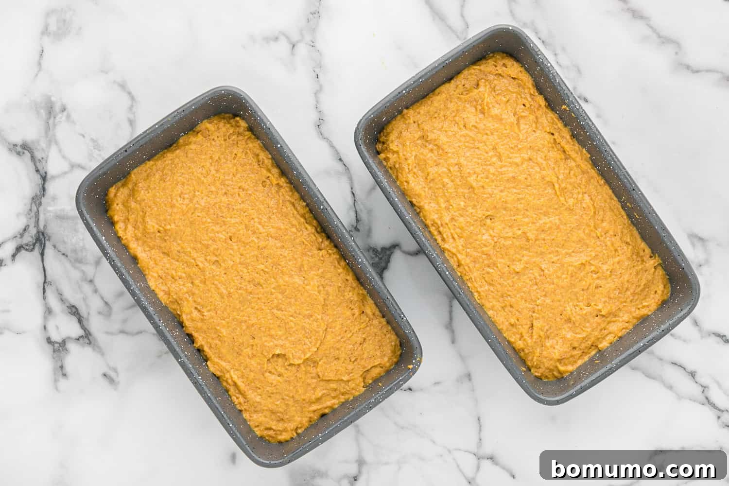 Unbaked, ungarnished healthy pumpkin bread batter evenly distributed in loaf pans, ready for the oven.