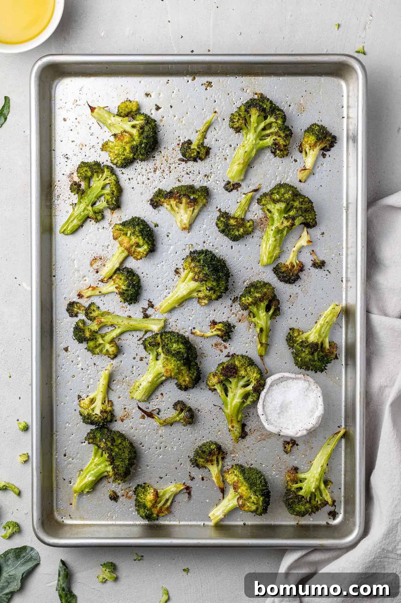 Overhead view of sheetpan full of roasted broccoli, perfectly golden and tender-crisp.