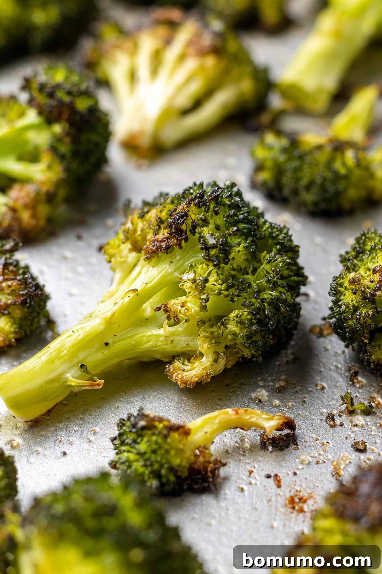 Bright green crispy roasted broccoli on a sheet pan, perfectly cooked and ready to serve.