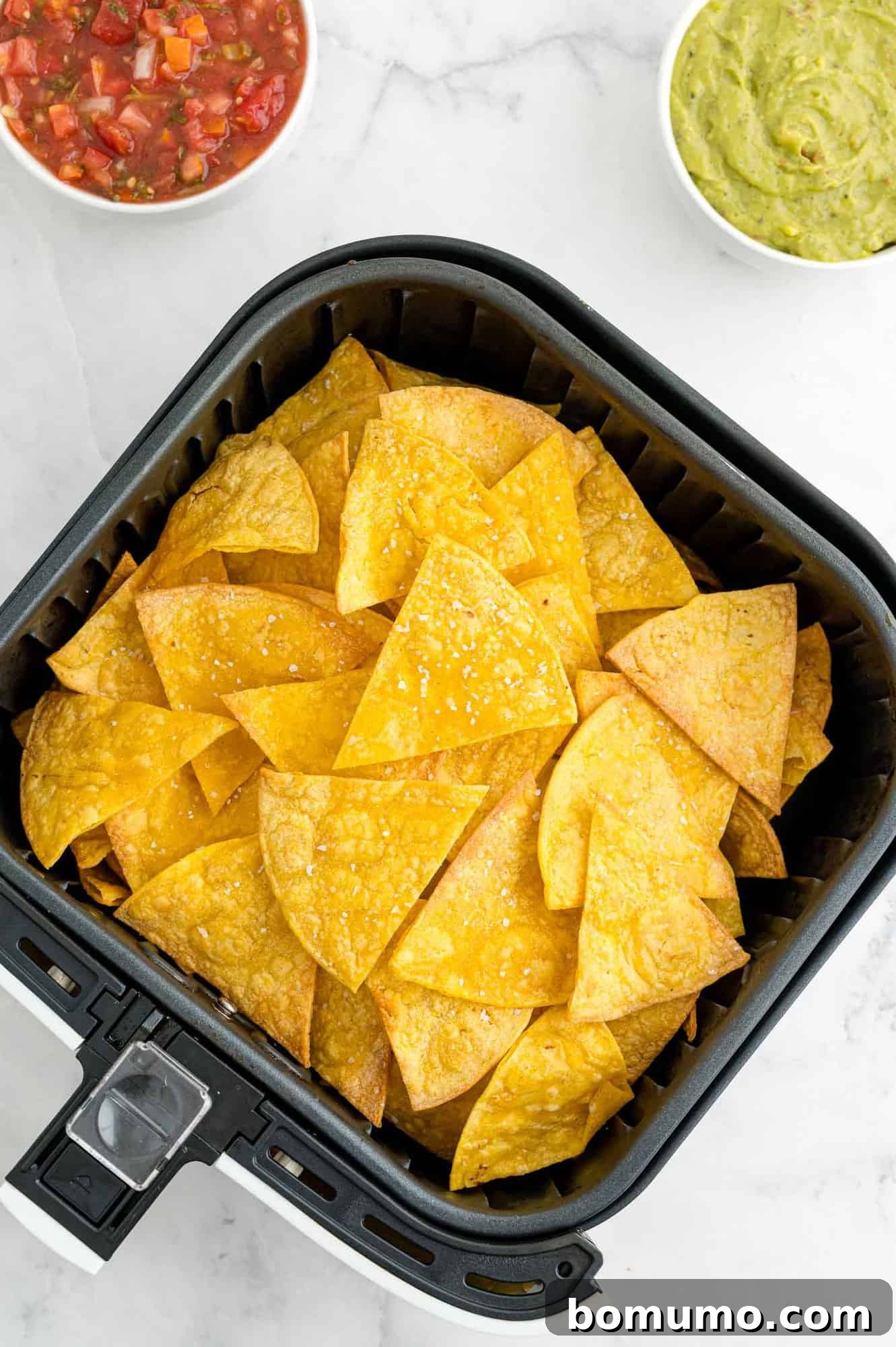 Perfectly golden-brown air fryer corn tortilla chips neatly arranged in an air fryer basket, ready to be enjoyed.