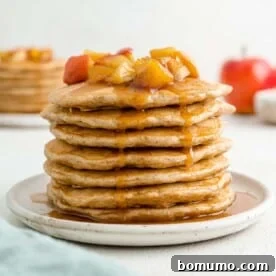 Tall stack of apple pancakes, topped with apple compote.