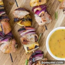 Pork kebobs with apples and onions, served with sauce.