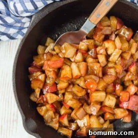 Apple compote in a cast iron skillet, with a spoon.