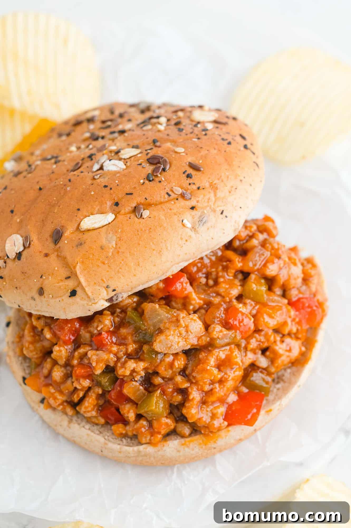 A perfectly assembled Sloppy Joe sandwich, with the top bun moved aside to showcase the rich, savory filling made with ground meat and colorful vegetables.