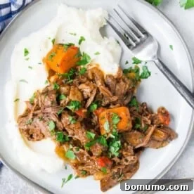 An overhead view of tender Italian pot roast served over creamy mashed potatoes.