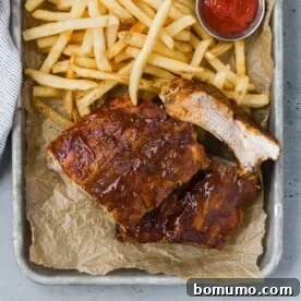 Succulent barbecued ribs on a tray with a side of crispy fries and ketchup.