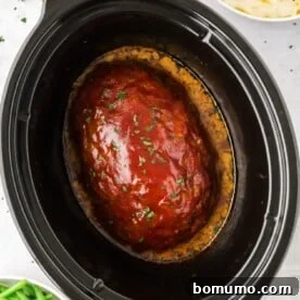 A perfectly glazed crockpot meatloaf, still in the slow cooker, ready to be sliced.