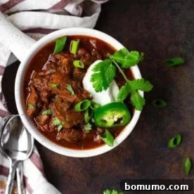 A hearty bowl of Slow Cooker Texas Chili, garnished with sour cream, cilantro, and jalapeños.