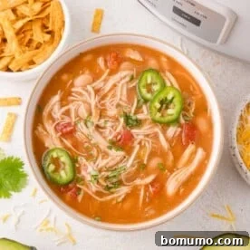 A comforting bowl of Crockpot White Chicken Chili, topped with sliced jalapeños and fresh herbs.