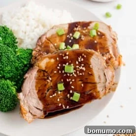 Two slices of slow cooker pork loin with balsamic glaze, beautifully plated.
