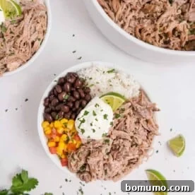 Flavorful pulled pork served in a bowl with rice, black beans, corn, and a dollop of sour cream.