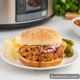 A delicious crockpot BBQ chicken sandwich on a bun, ready to eat.