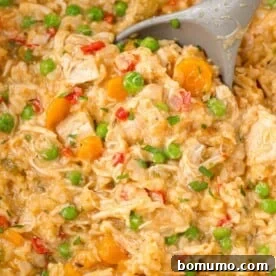Hearty crockpot chicken and rice casserole being scooped with a serving spoon.