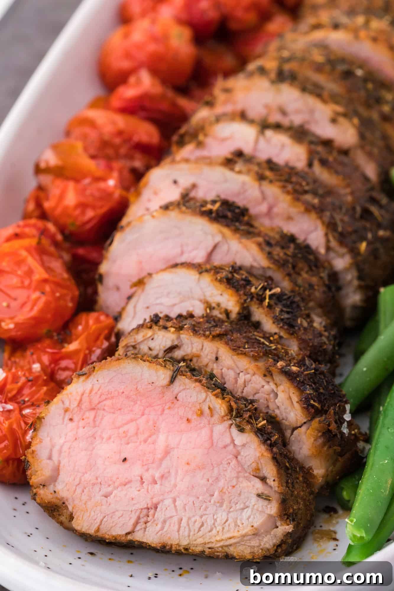 Spiced rubbed pork tenderloin, sliced and plated, garnished for serving.