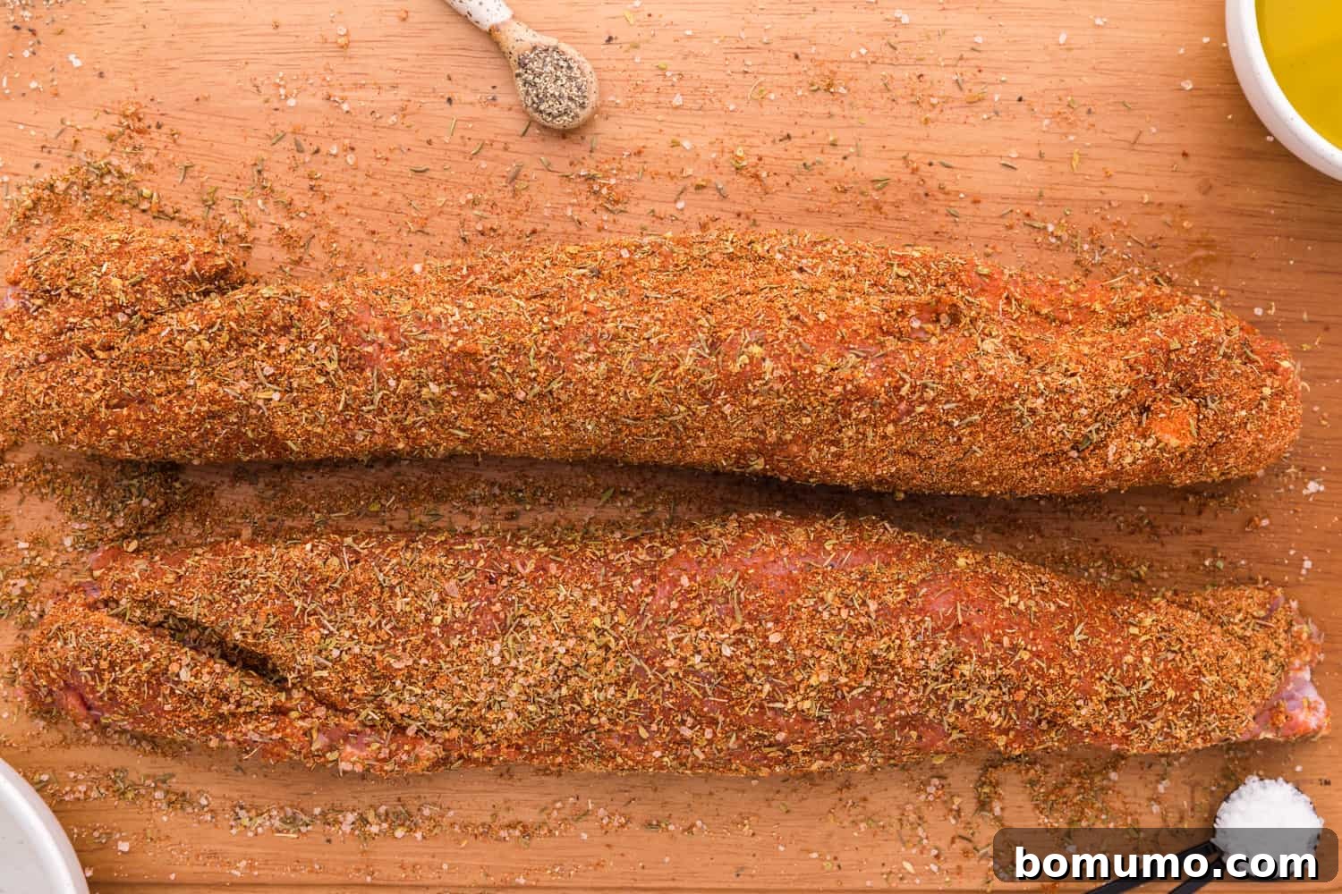 Uncooked tenderloins, thoroughly rubbed with spices, ready for cooking.