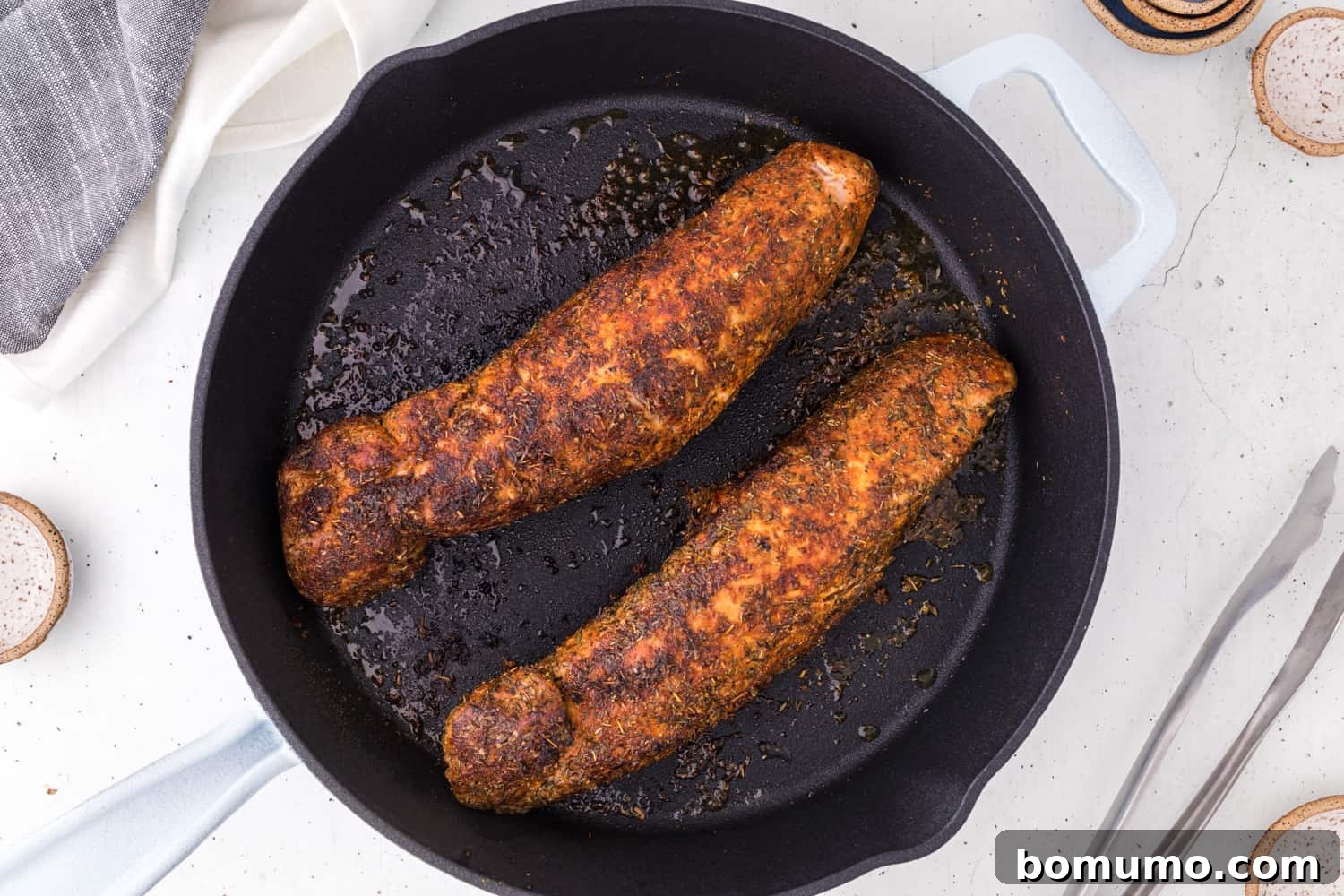 Perfectly seared pork tenderloins resting in a cast iron skillet after baking.