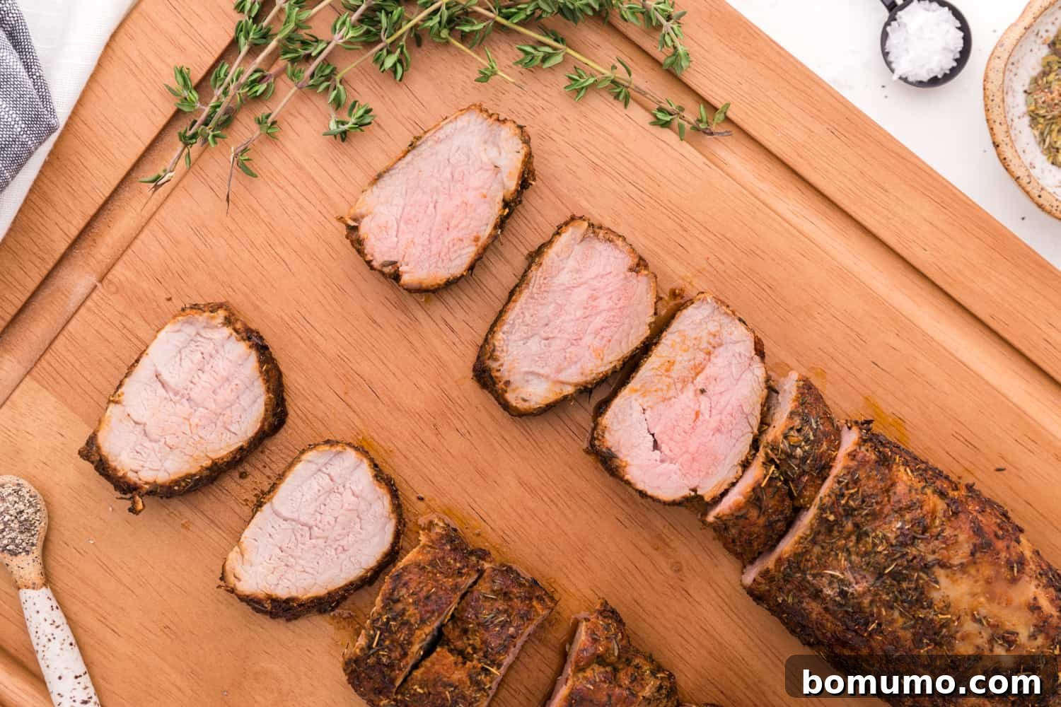 Partially sliced pork tenderloins on a cutting board, ready to be served.