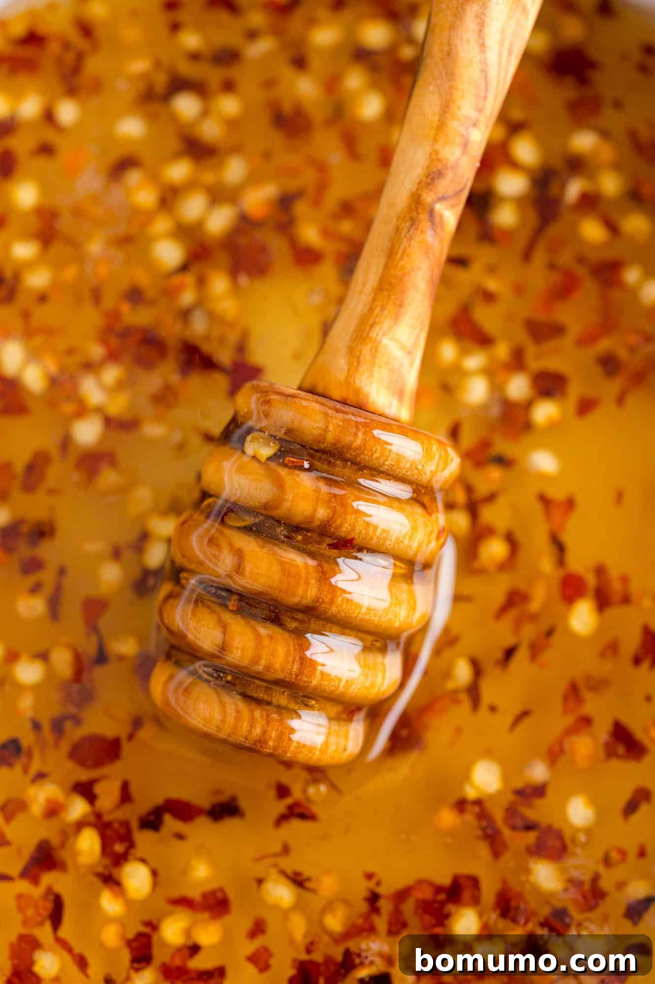 Close up of hot honey and honey dipper, showcasing the rich golden color and subtle spice.
