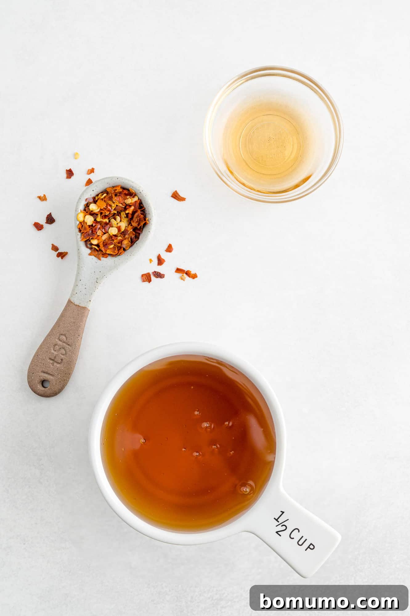 Overhead view of the simple ingredients needed to make hot honey: honey, red pepper flakes, and apple cider vinegar.