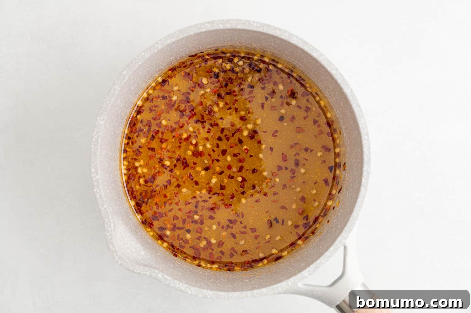 Honey with red pepper flakes in a saucepan on the stovetop, just before simmering.
