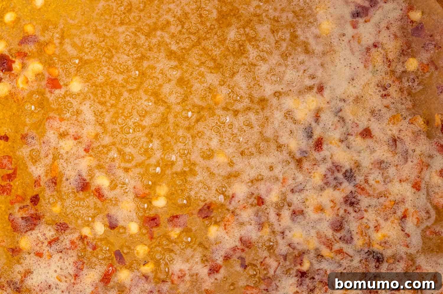 Honey simmering gently in a saucepan, with small bubbles visible.