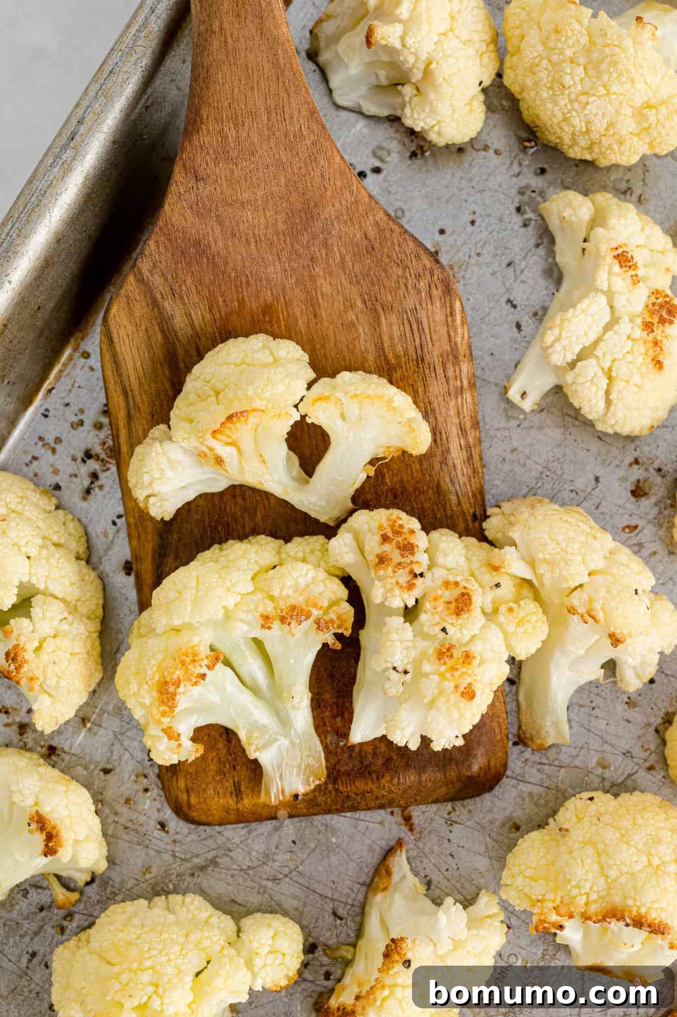 Perfectly Crispy Roasted Cauliflower 2 Cauliflower on a wooden spatula, freshly roasted and golden brown.
