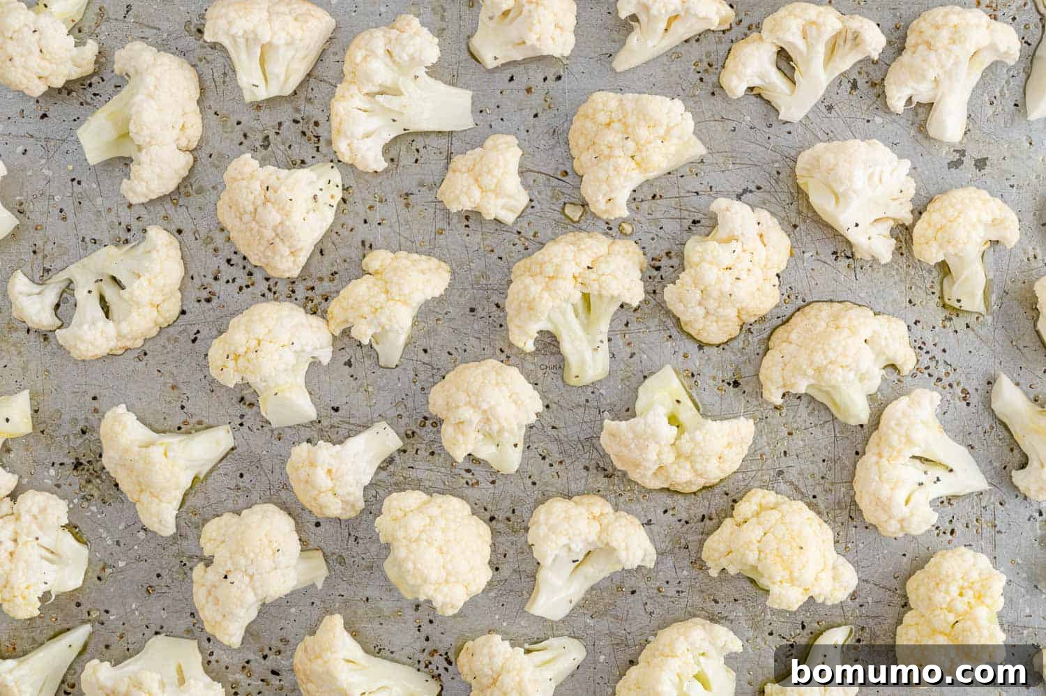 Perfectly Crispy Roasted Cauliflower 11 Uncooked cauliflower florets spread in a single layer on a baking sheet.